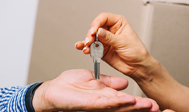 Imagem de uma pessoa entregando as chaves de um imóvel para outra