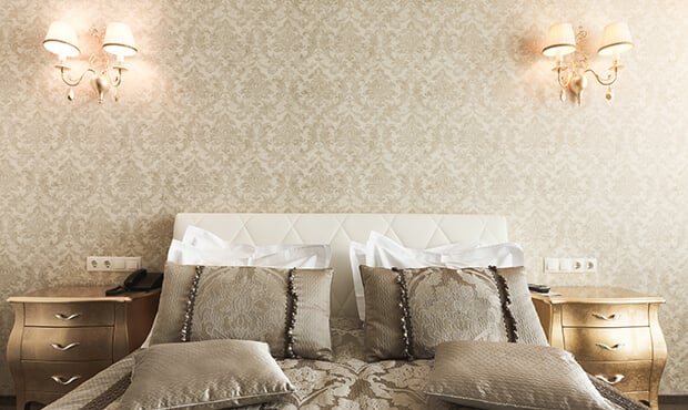 Imagem de um quarto de casal com luminárias e cama