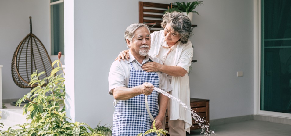 casal de idosos cuidando da casa regando o jardim